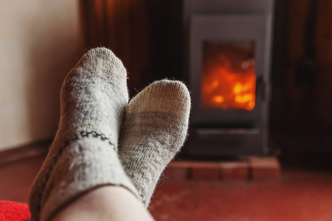 56352399-feet-legs-in-winter-clothes-wool-socks-at-fireplace
